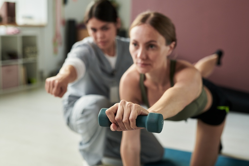 Women engaging in fitness routine while lifting dumbbells in a gym setting with focus and dedication. Fitness equipment present in background