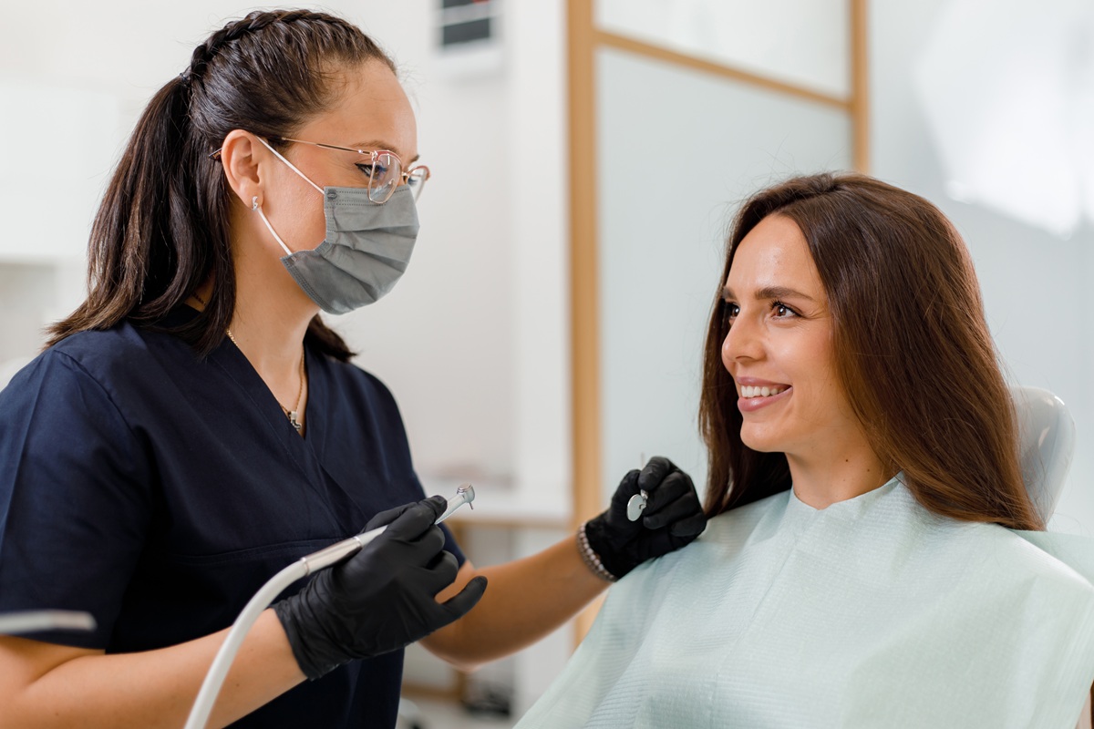 A dental hygienist assists a patient in a bright, contemporary clinic, preparing for a routine dental checkup while maintaining a calm and friendly atmosphere.