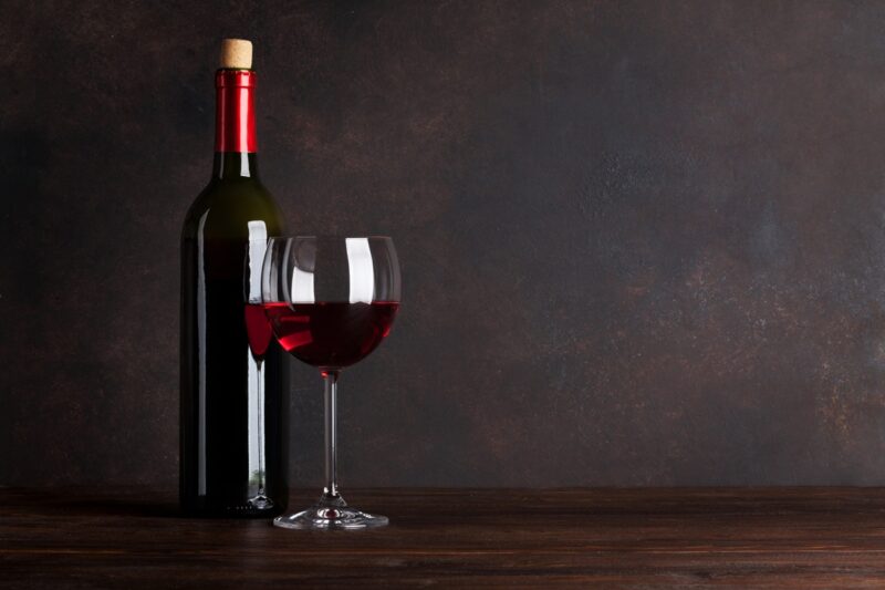 Red wine bottle and glass in front of blackboard wall. With copy space for your text