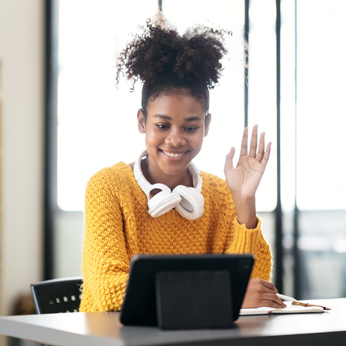 African american student woman in sweater video conference on tablet to studying lesson online class and greeting with classmates while sitting to learning knowledge and education in university.
